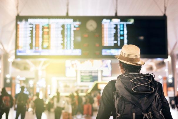 Young traveler looking at airport time board for flight