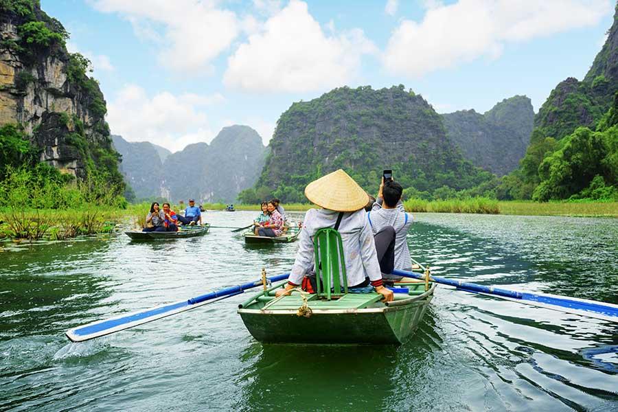 Tourists traveling in small boat along Ngo Dong River, Vietnam