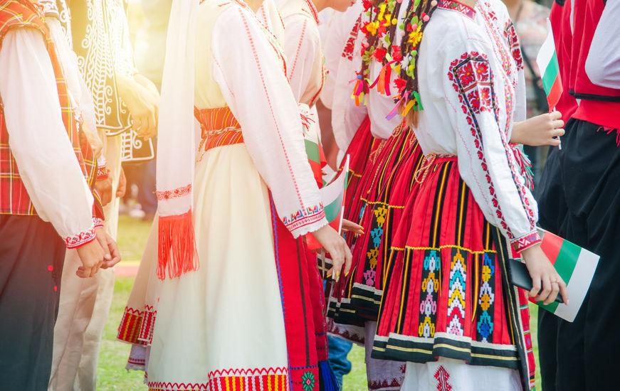 Unrecognizable irls in ethnic Bulgarian costumes with colorful ornament